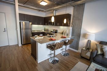 a kitchen and living room with pendant lighting and plank flooring at The Parker, Portland 97209